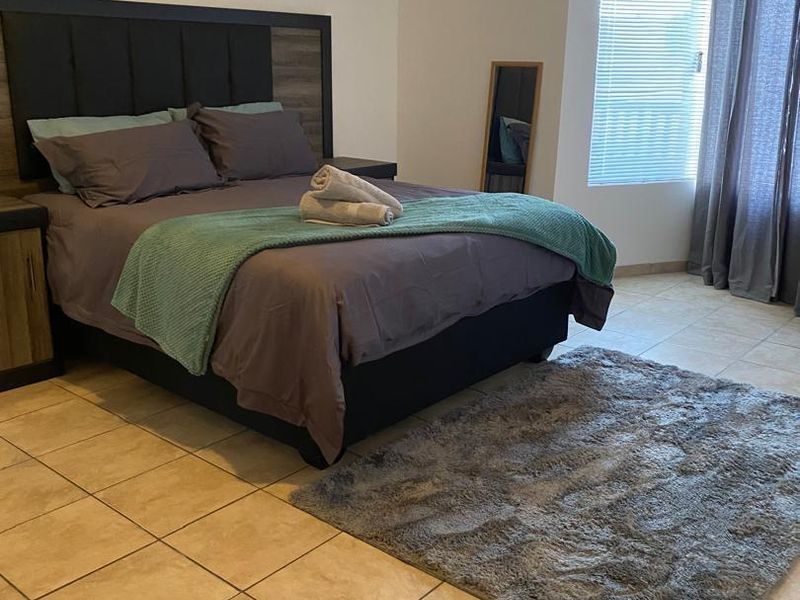 A bedroom featuring tiled flooring, window blinds, and curtain tracks, providing a functional space with neutral finishes.