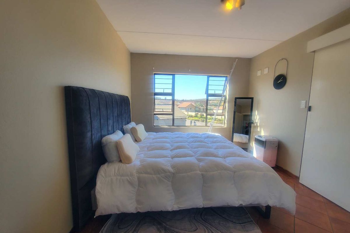 A bedroom featuring tiled flooring, a large window with natural light, and a built-in sliding door closet.