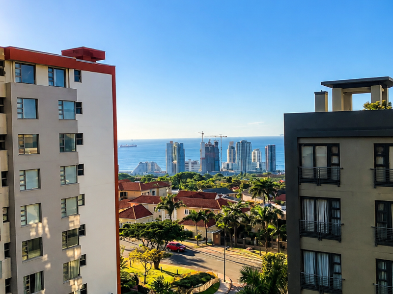 A scenic elevated view overlooking the surrounding neighborhood, street, and distant ocean horizon from a balcony.