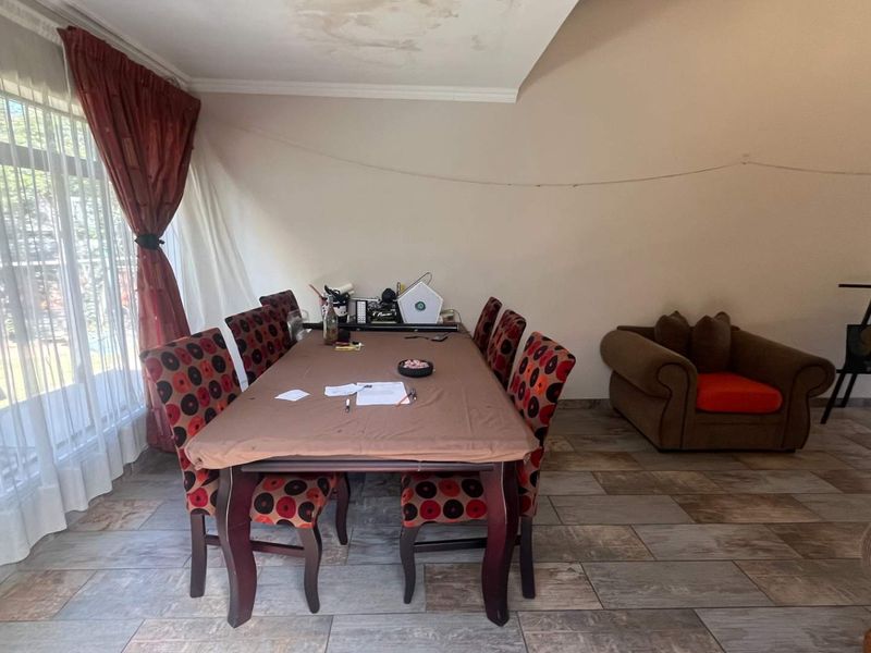 Dining room featuring tiled flooring and a large sliding glass door, with visible water staining on the ceiling requiring attention.