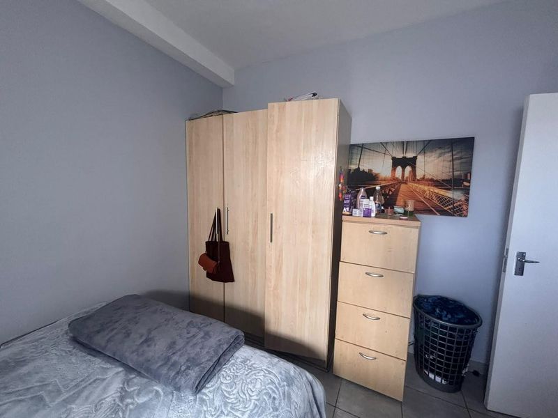 A functional bedroom featuring a light wood-finish built-in wardrobe and tiled flooring, providing a neutral base for personalization.