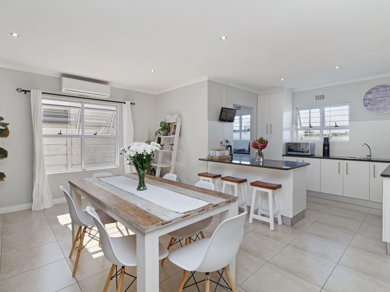 Bright open-plan living and dining area featuring a modern kitchen with granite countertops, built-in cabinetry, and tiled flooring throughout.