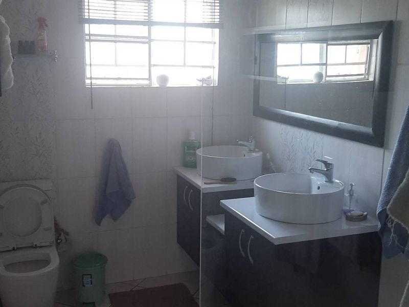 A functional bathroom featuring a dual vanity with vessel sinks, wall-mounted toilet, and tiled finishes, providing a practical layout for daily use.