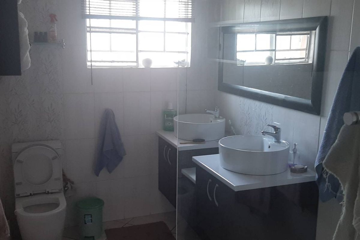 A functional bathroom featuring a dual vanity with vessel sinks, wall-mounted toilet, and tiled finishes, providing a practical layout for daily use.