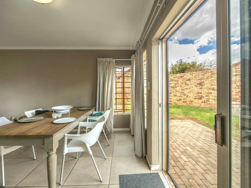 Open plan living area featuring tiled floors and large sliding glass doors providing direct access to a paved patio and private garden.