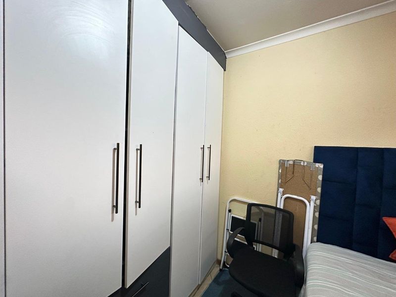 A bedroom featuring floor-to-ceiling built-in cupboards with modern handles and decorative coving.