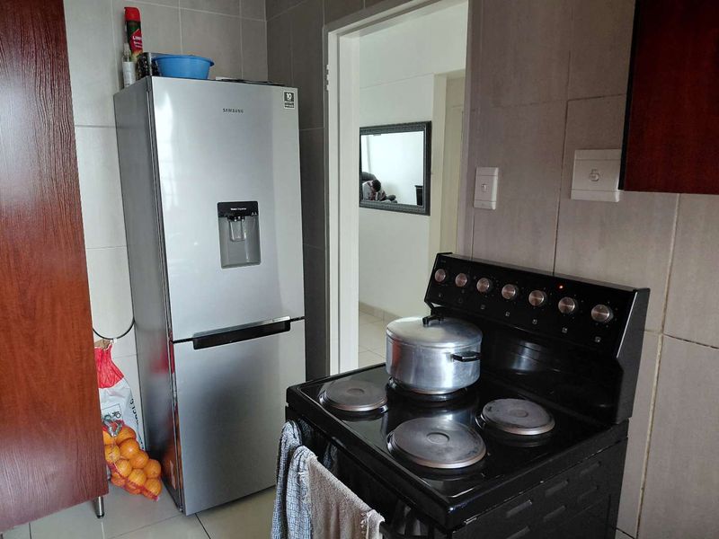 A functional kitchen area featuring tiled walls, tiled flooring, and built-in cabinetry, providing a practical space for daily cooking and food preparation.
