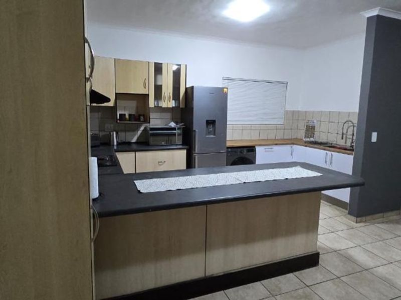 A functional kitchen featuring built-in cabinetry, a central island, tiled backsplash, and tiled flooring, providing a practical layout for daily cooking and meal preparation.