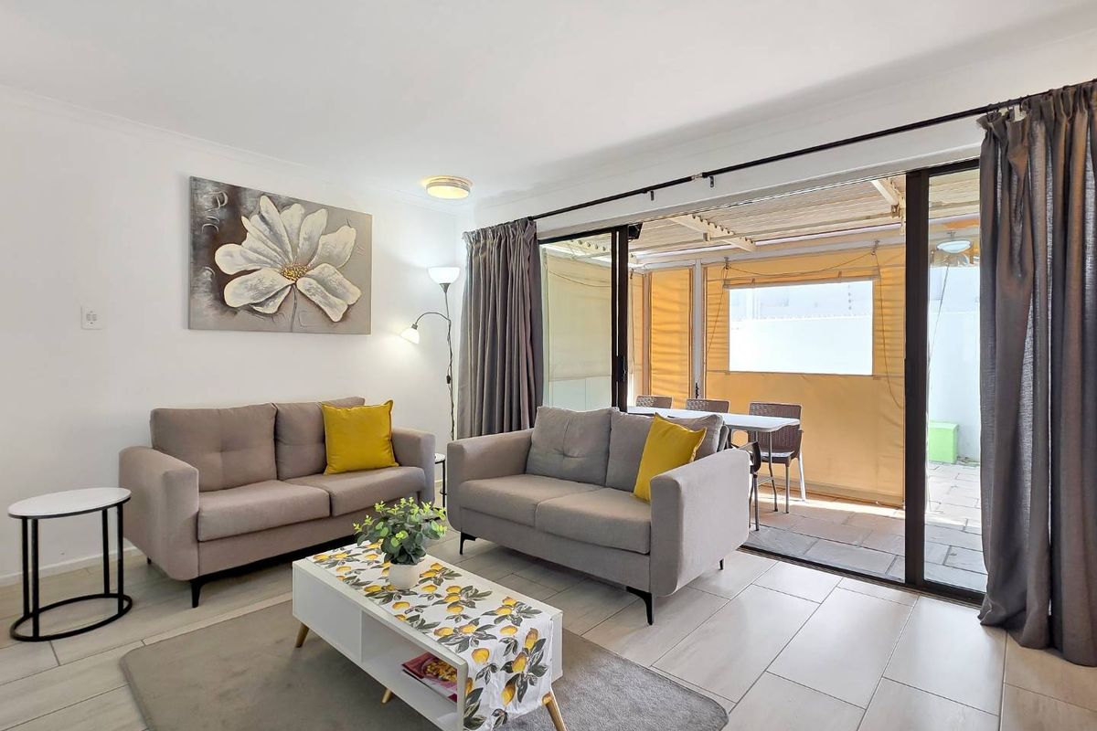 A bright living room featuring large sliding glass doors that open onto a covered patio area, creating a seamless indoor-outdoor flow.