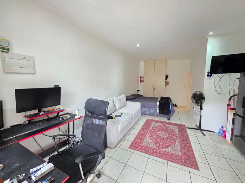 Open-plan studio apartment featuring tiled flooring, recessed lighting, and built-in cupboard storage, offering a functional living and sleeping space.