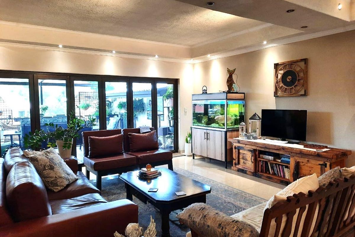 Spacious living room featuring recessed ceiling lighting, tiled flooring, and large folding glass doors that provide seamless access to the outdoor patio area.