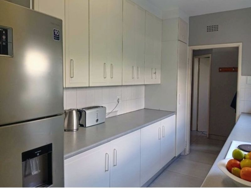 A functional kitchen featuring white built-in cabinetry, grey laminate countertops, and a tiled backsplash, providing a clean and practical workspace.