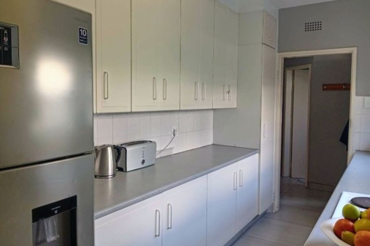 A functional kitchen featuring white built-in cabinetry, grey laminate countertops, and a tiled backsplash, providing a clean and practical workspace.