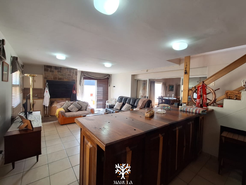 Spacious open-plan living area featuring a stone fireplace, built-in bar counter, and direct access to the outdoor patio through sliding glass doors.