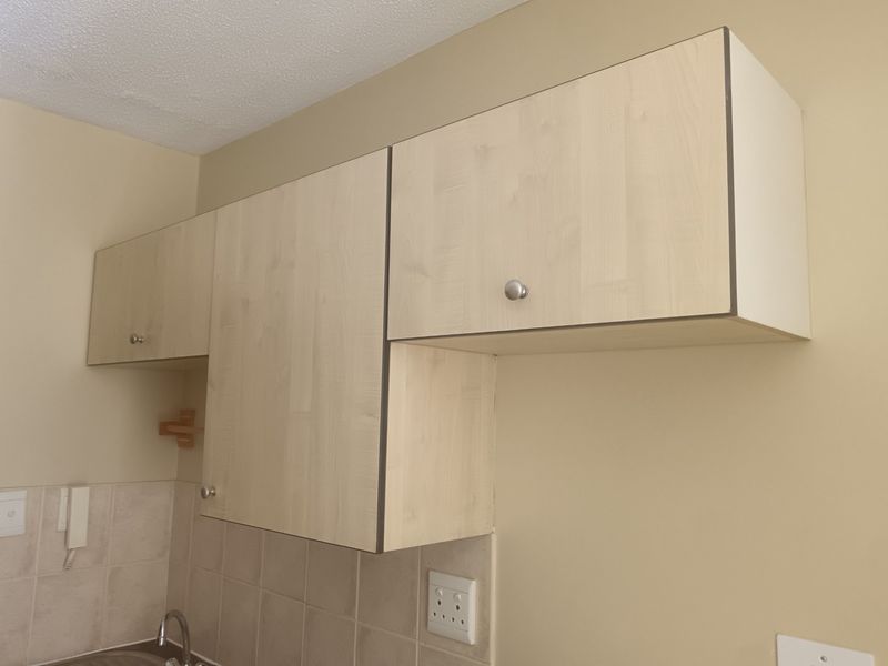 A close-up view of kitchen wall-mounted cabinetry with a tiled backsplash and integrated electrical fixtures.