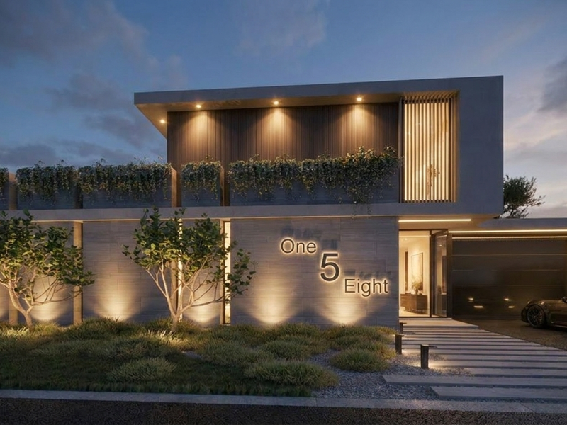 A modern architectural front elevation featuring integrated facade lighting, built-in planters, and a sleek driveway entrance.