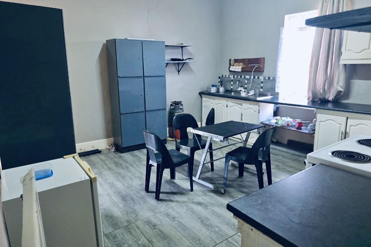 A functional kitchen space featuring tiled flooring, built-in cabinetry, and a tiled backsplash, requiring cosmetic updates to improve its overall condition.