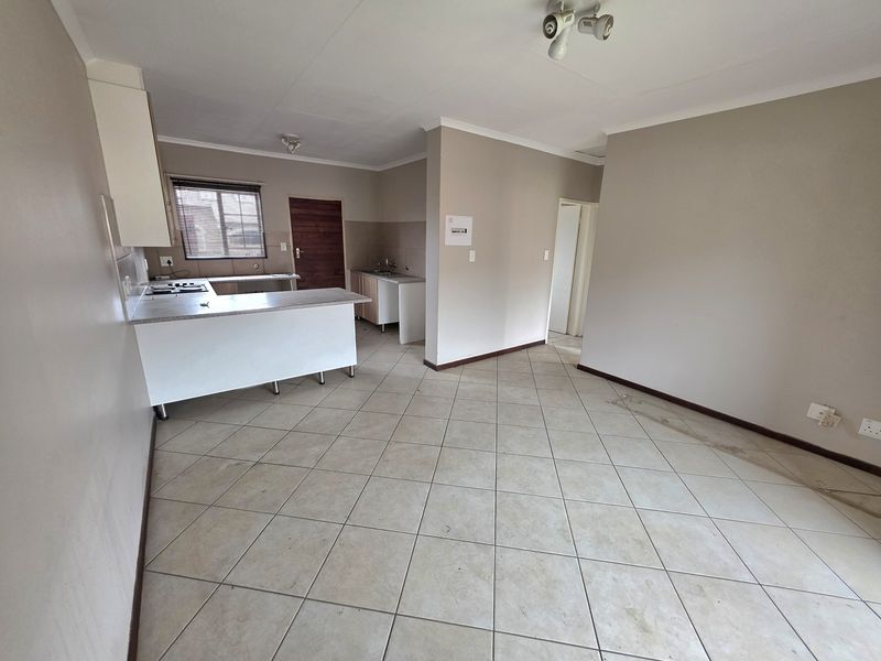 Open-plan living and kitchen area featuring tiled flooring, built-in cabinetry, and a gas hob, offering a functional blank canvas for personalization.