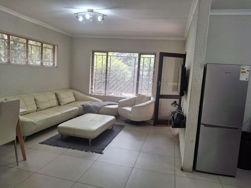 A living room featuring tiled flooring, coved ceilings, and large windows fitted with security bars and venetian blinds.