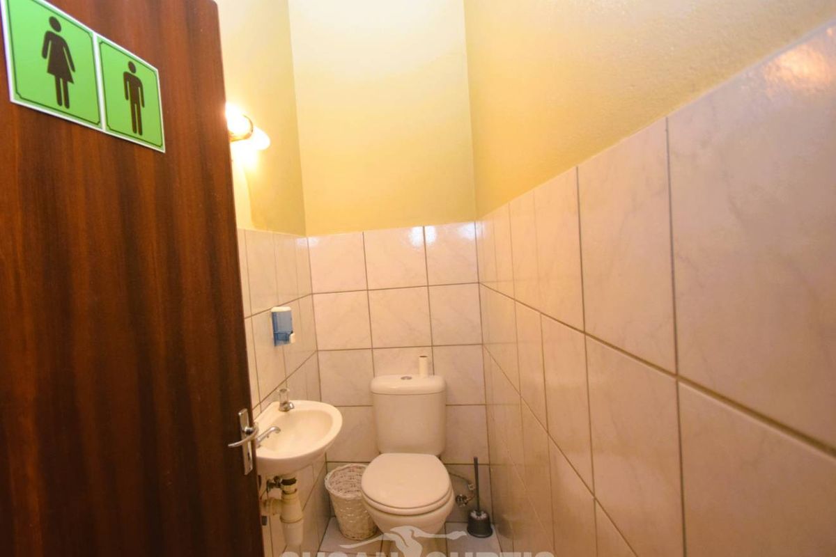 A compact guest bathroom featuring a wall-mounted basin and a standard toilet with tiled walls.