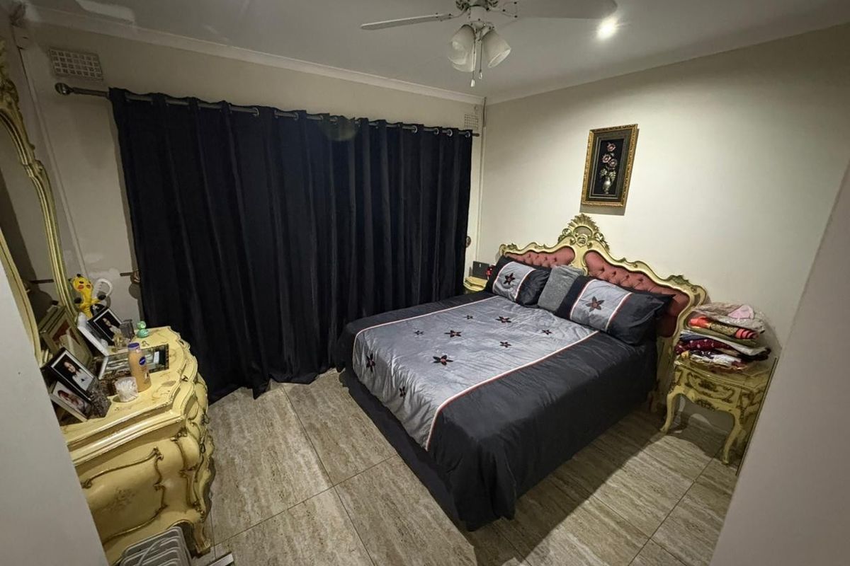 A bedroom featuring tiled flooring and a ceiling fan, providing a functional space with neutral wall finishes.