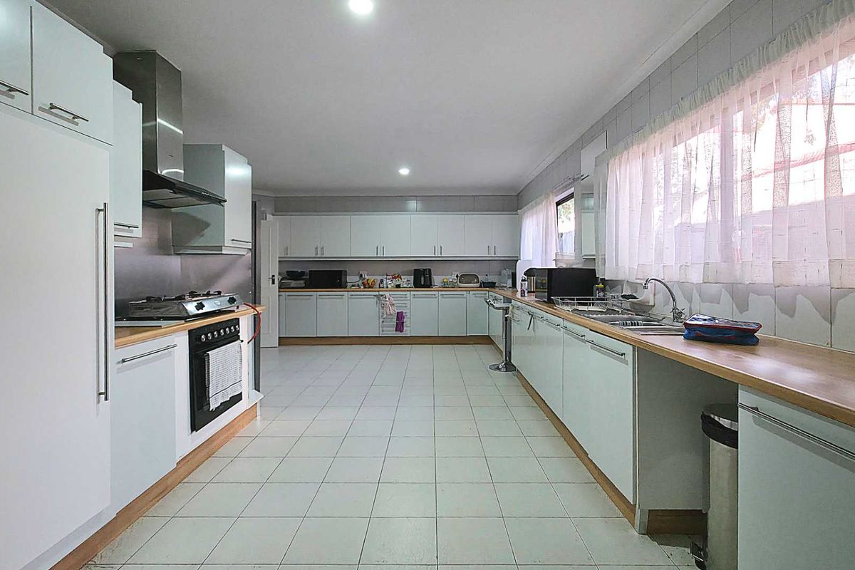 Spacious kitchen featuring extensive white cabinetry, laminate countertops, a gas hob with extractor, and tiled flooring.