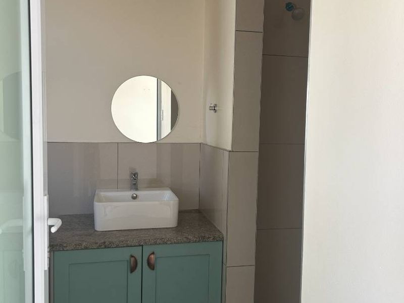 A clean, modern bathroom featuring a vanity with a vessel sink, tiled shower area, and neutral wall finishes.