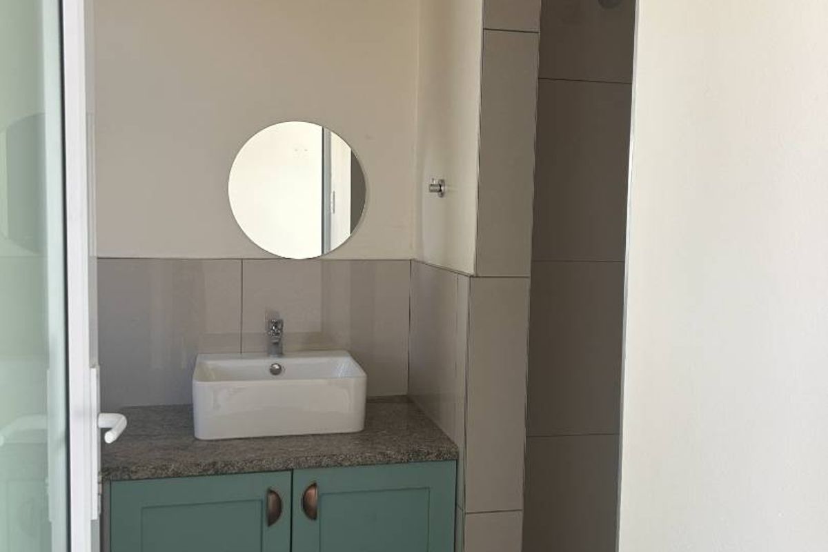 A clean, modern bathroom featuring a vanity with a vessel sink, tiled shower area, and neutral wall finishes.