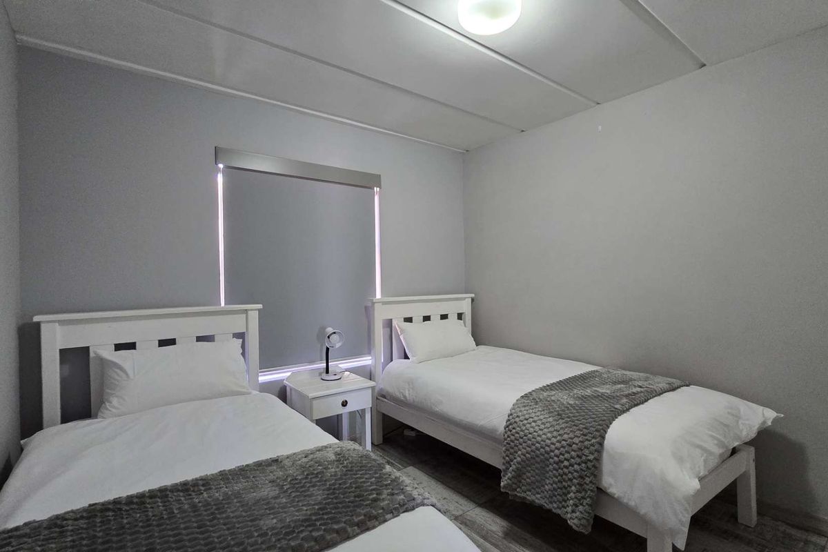 A functional bedroom featuring tiled flooring, neutral wall finishes, and a roller blind for privacy.