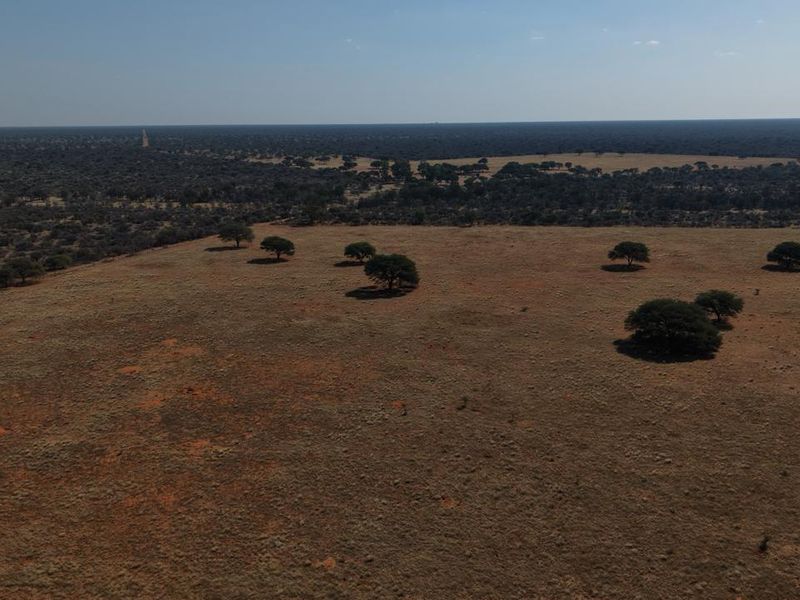 An aerial view of the expansive farm property, showcasing open grazing land and scattered native trees across the landscape.