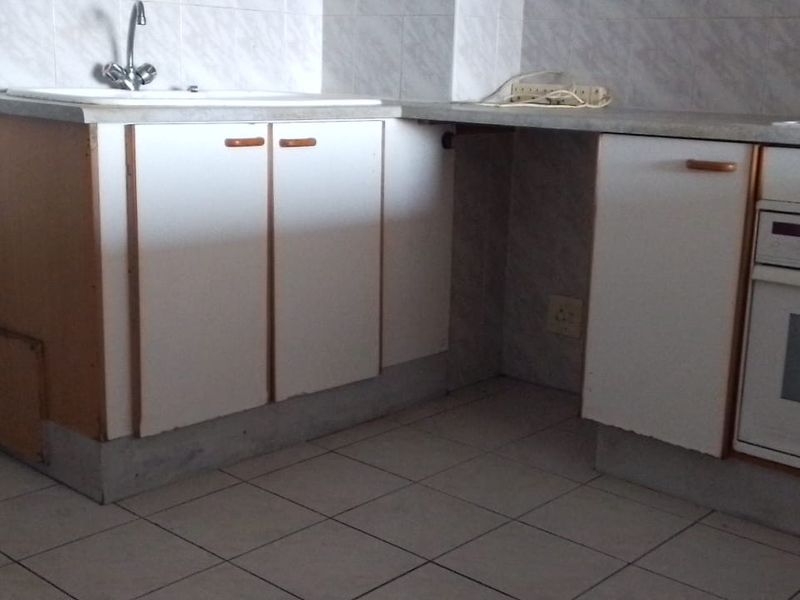 A functional kitchen space featuring built-in cabinetry, a sink, and an integrated oven, requiring cosmetic updates to modernize the dated finishes.