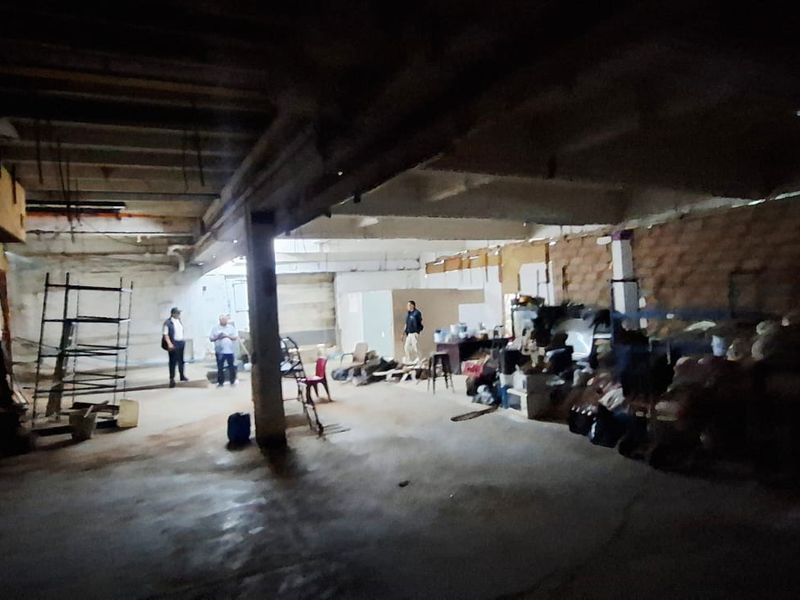 Large industrial utility space featuring exposed concrete structure, brick walls, and a metal staircase, suitable for warehouse or workshop conversion.