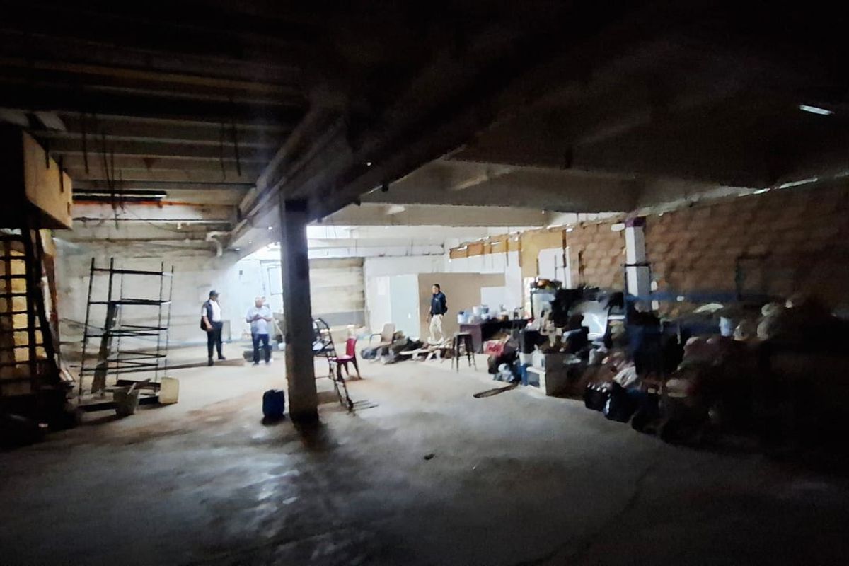 Large industrial utility space featuring exposed concrete structure, brick walls, and a metal staircase, suitable for warehouse or workshop conversion.