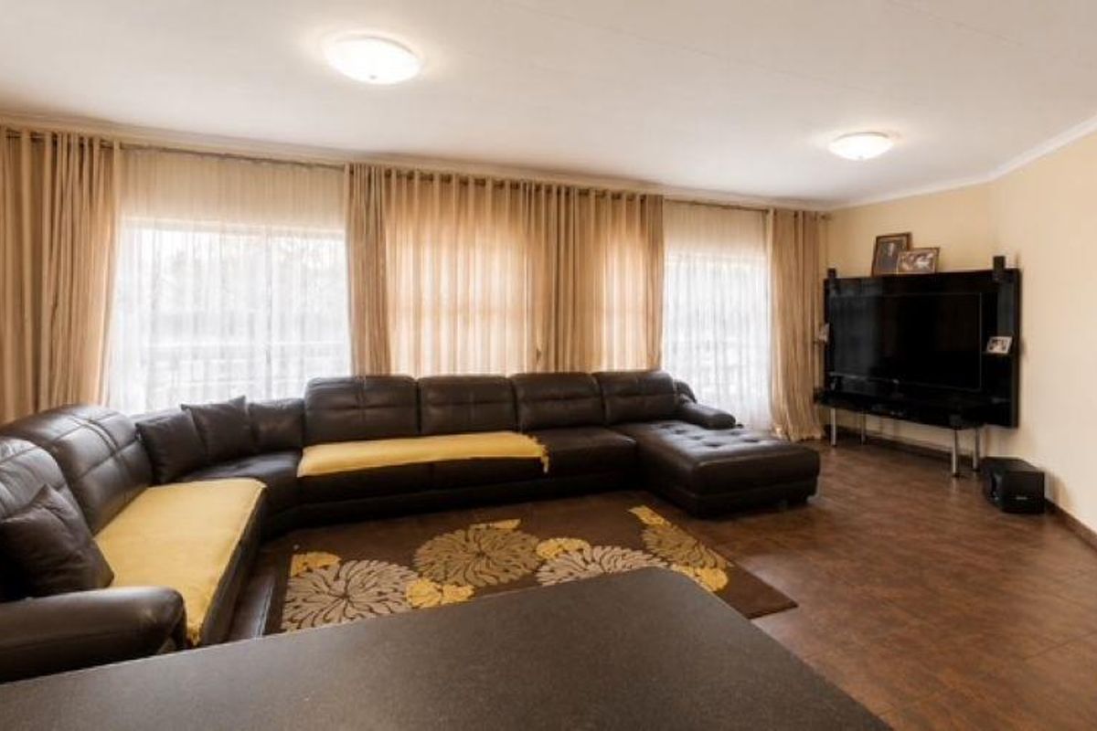 Spacious living room featuring tiled flooring, neutral walls, and large windows with floor-to-ceiling curtains, providing a comfortable and well-lit area.