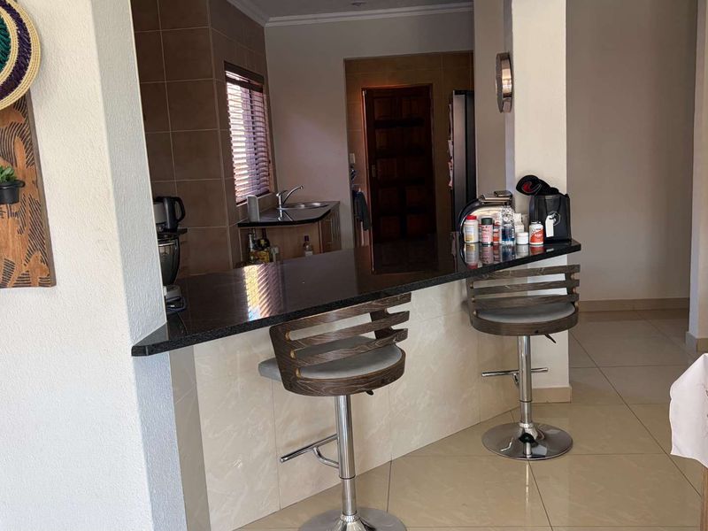 Open plan living area featuring a granite breakfast bar counter and tiled flooring, seamlessly connecting to the kitchen space.