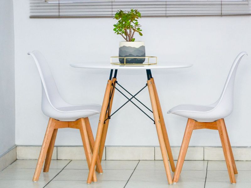 A simple dining area featuring tiled flooring and venetian blinds, providing a clean and functional space.