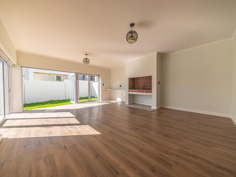 Spacious open-plan living area featuring modern laminate flooring, a built-in fireplace, and large stacking doors opening to the garden.