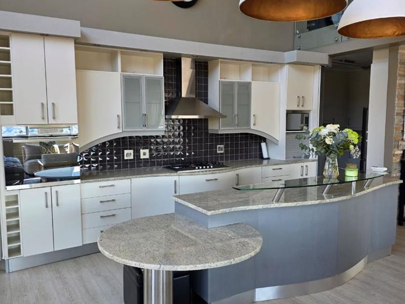 Modern kitchen featuring granite countertops, a breakfast bar, built-in cabinetry, and high-quality stainless steel appliances, offering a functional and stylish cooking space.
