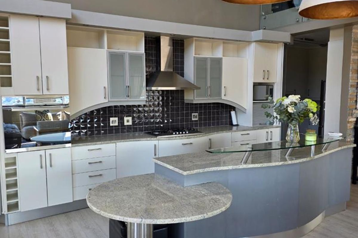 Modern kitchen featuring granite countertops, a breakfast bar, built-in cabinetry, and high-quality stainless steel appliances, offering a functional and stylish cooking space.
