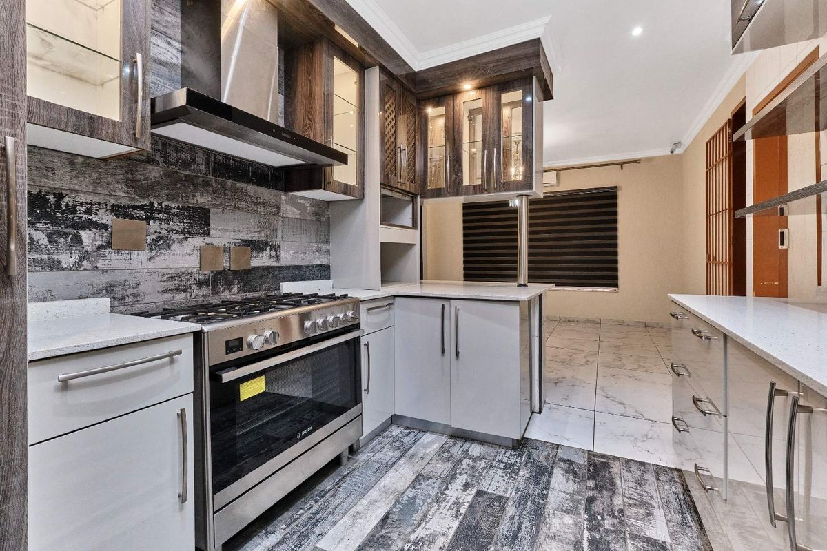 Modern kitchen featuring high-quality cabinetry, stone countertops, a gas stove with extractor fan, and stylish tiled flooring throughout.