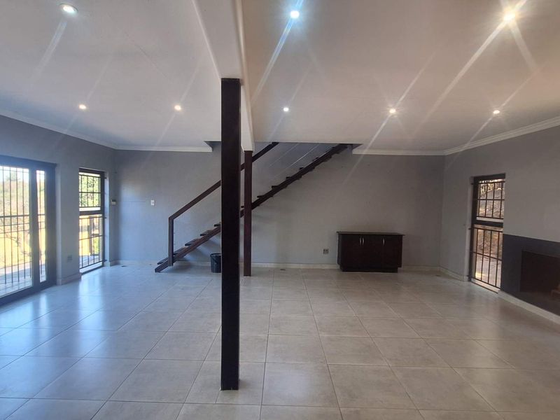 Spacious open-plan living area featuring tiled floors, a modern staircase, a built-in fireplace, and large sliding doors leading to an outdoor space.