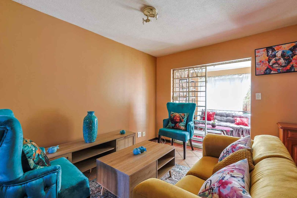 A living room featuring a sliding glass door with security gate leading to an outdoor patio area.