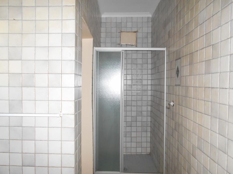A functional bathroom featuring a shower enclosure with full-height wall tiling and an integrated extractor fan.