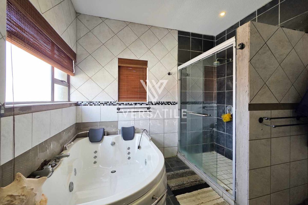 A spacious bathroom featuring a corner jetted bathtub, a separate glass-enclosed shower, and tiled wall finishes.