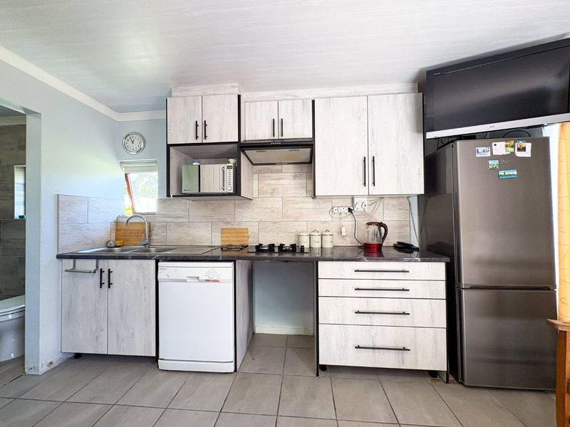 A functional kitchen featuring light wood-grain cabinetry, tiled backsplash, and integrated storage, with space for a dishwasher and additional appliances.