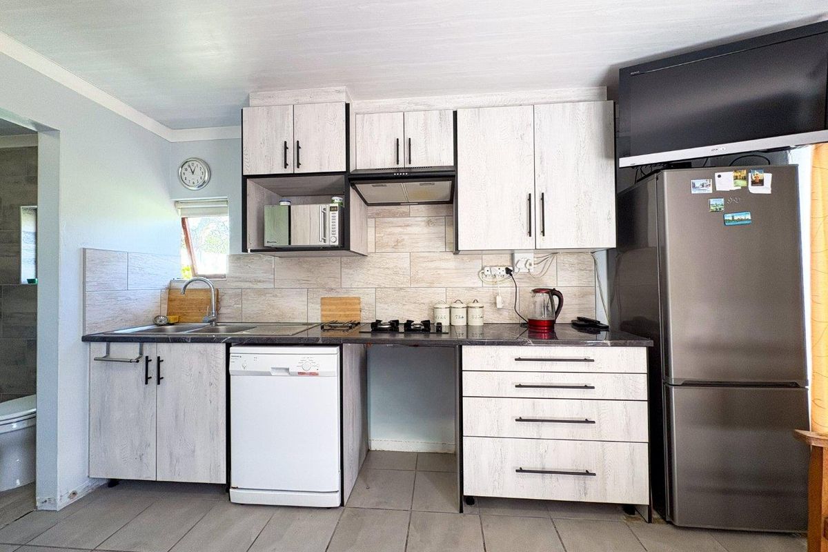 A functional kitchen featuring light wood-grain cabinetry, tiled backsplash, and integrated storage, with space for a dishwasher and additional appliances.