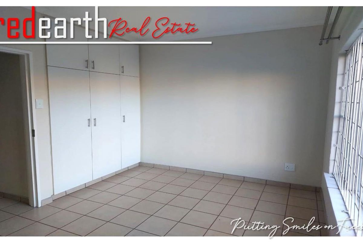 A bright, empty bedroom featuring neutral tiled flooring and built-in white cabinetry, offering a clean and versatile space.
