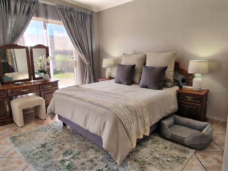 A well-maintained bedroom featuring tiled flooring and a sliding glass door providing access to the exterior.