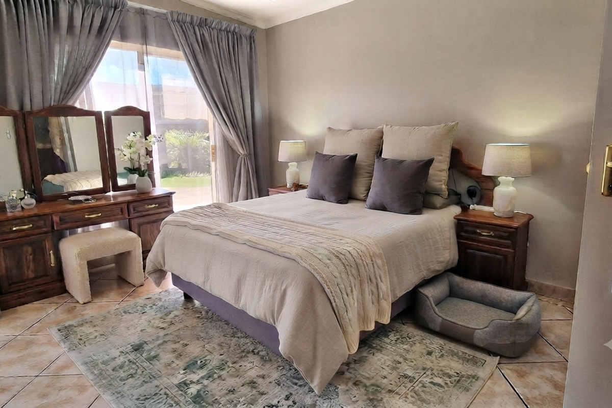 A well-maintained bedroom featuring tiled flooring and a sliding glass door providing access to the exterior.