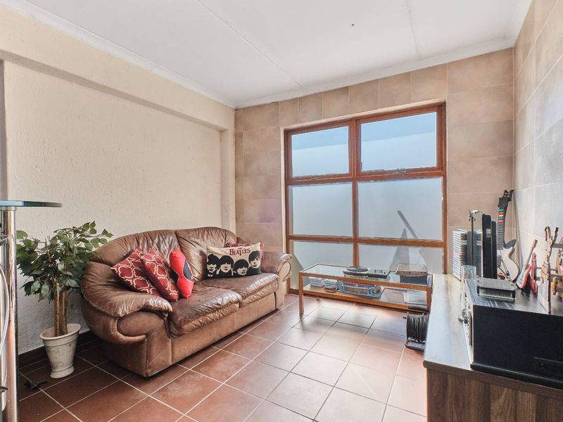 A living area featuring tiled flooring, tiled wall accents, and a large timber-framed window providing natural light.